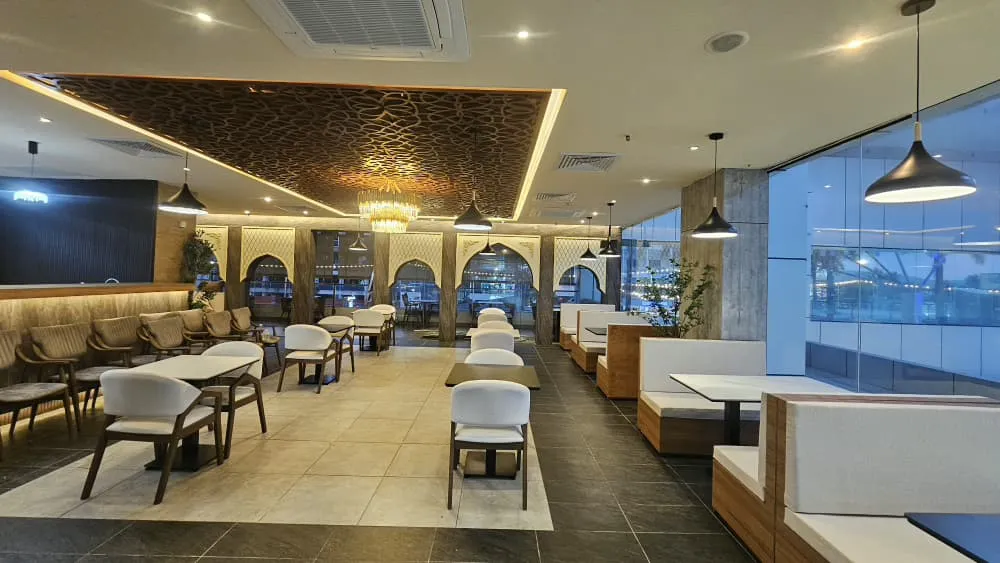 Dining hall with arched screens, carved ceiling panel and booth seating at Habak Al Sham, Cenang Mall