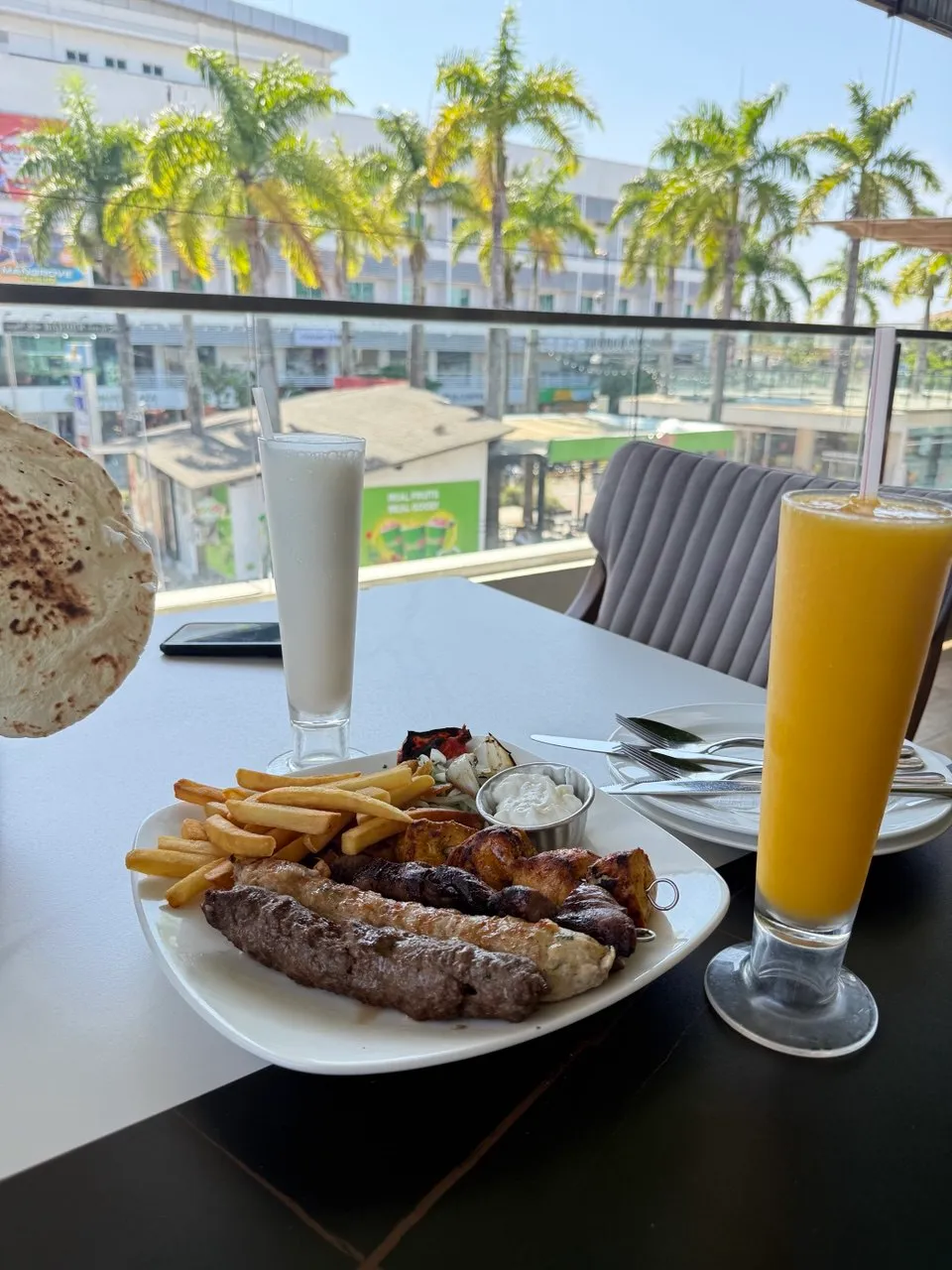 Mixed grill platter with kofta, chicken skewers, fries and garlic dip at a window table over the Pantai Cenang strip