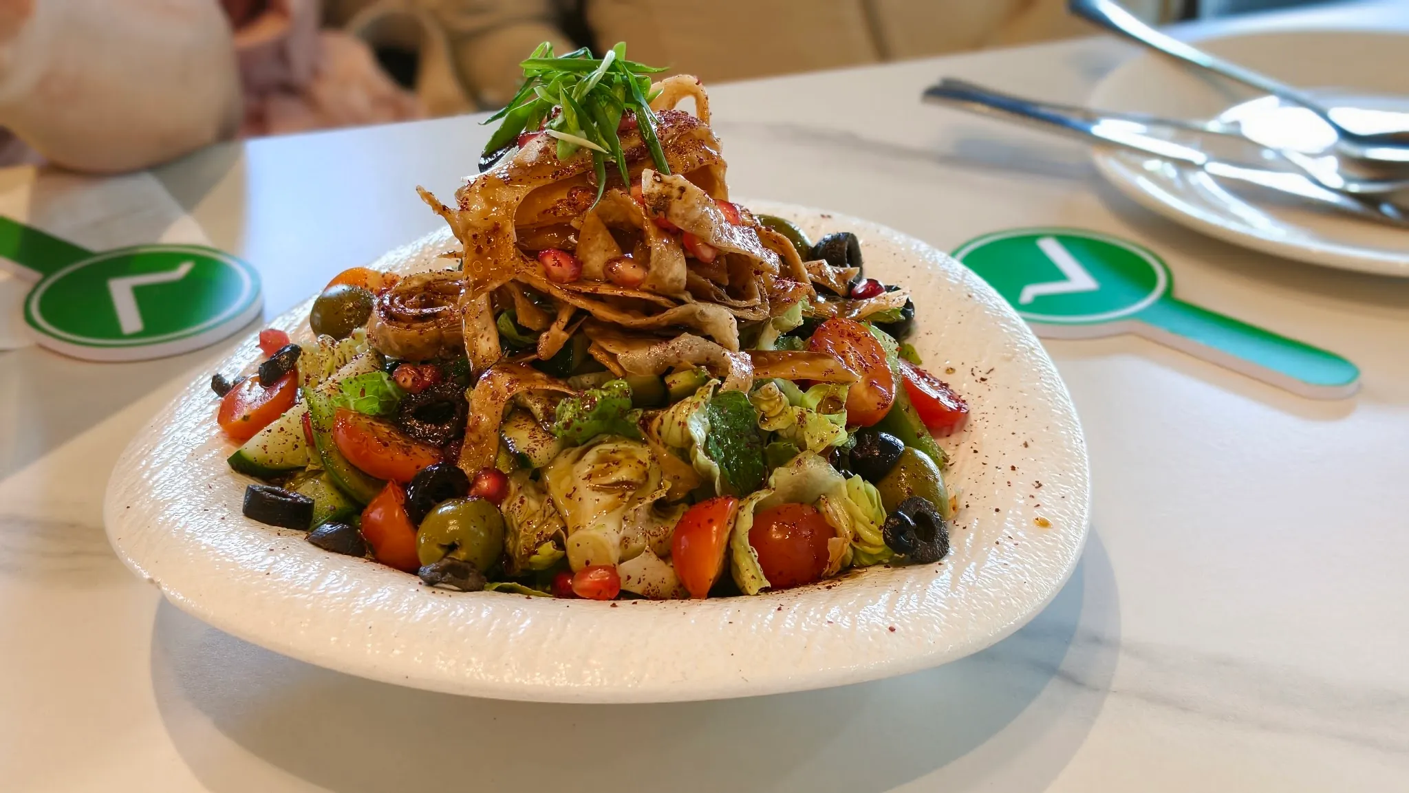 Fattoush salad with cherry tomatoes, olives, pomegranate seeds, sumac and crisp fried bread