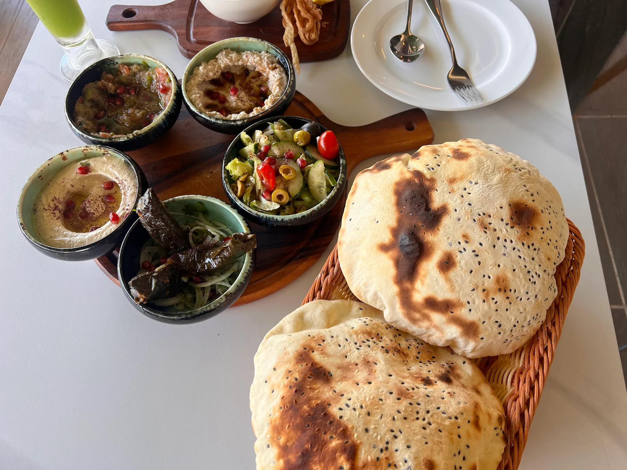 Mezze spread with hummus, moutabal, stuffed vine leaves and salad, served with puffed sesame flatbread fresh from the oven